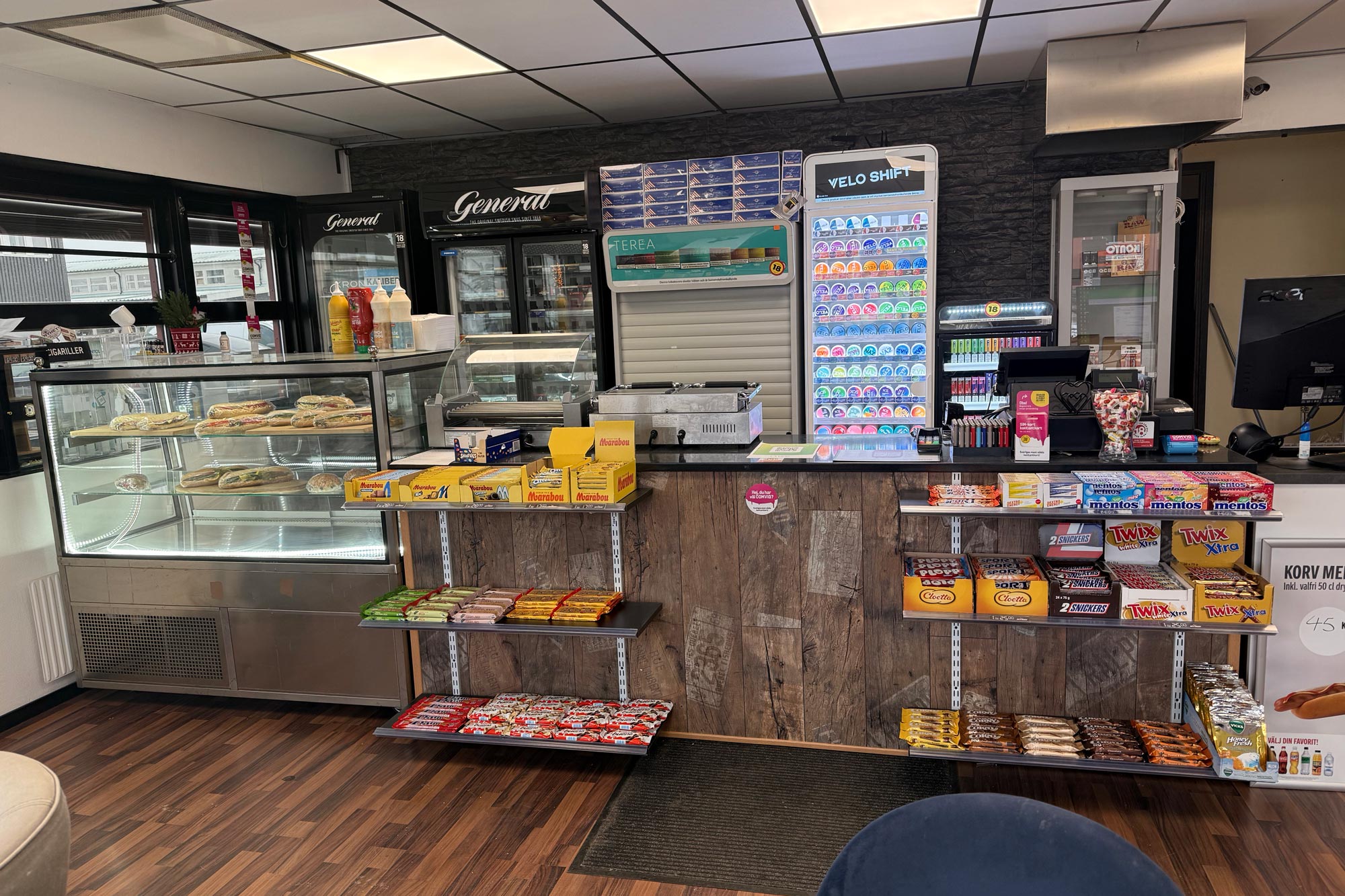 Interiör av kiosken med kassa, färska mackor, godis och nikotinprodukter